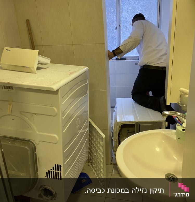 אדם עובד על מכונת כביסה בחדר אמבטיה